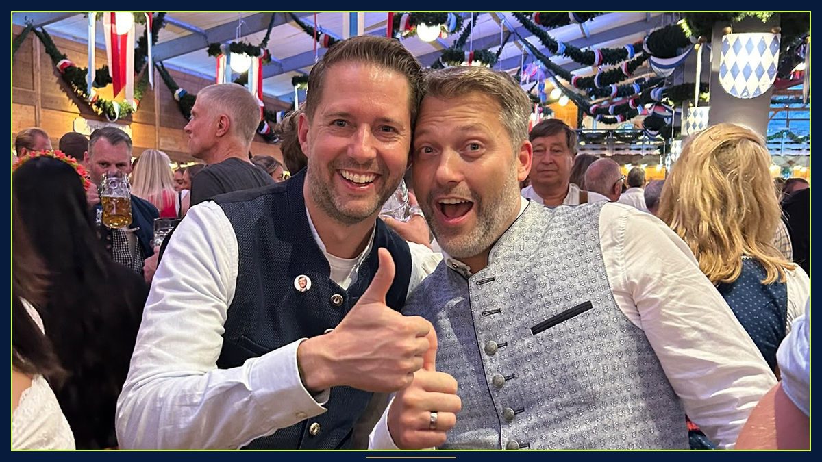 Andreas S. und Reinhard S. stehen in Tracht mit ausgelassener Mimik eng beieinander im Festzelt.